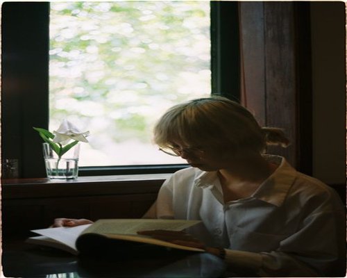 A person reading a book near a bright window